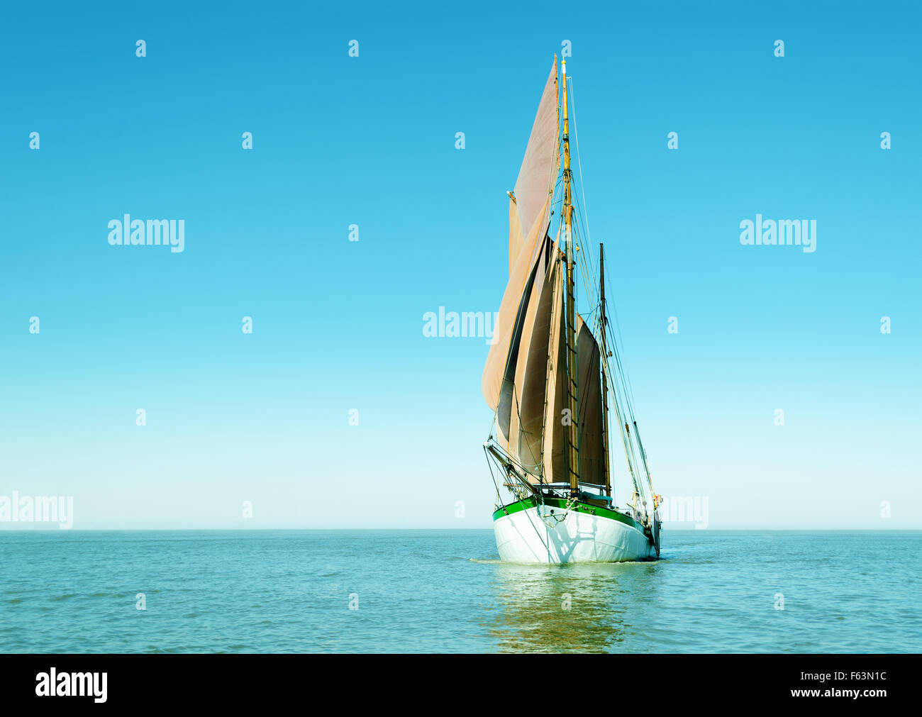 Tradizionale nave a vela da soli sull'oceano. Immagine luminosa principalmente con il colore ciano. Foto Stock
