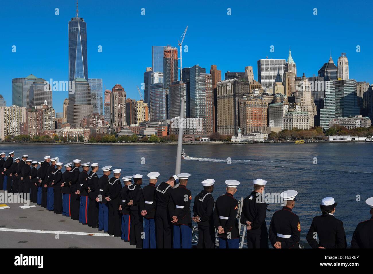 Gli Stati Uniti I marinai della marina militare e Marines stand al resto parata mentre manning le rotaie a bordo della San Antonio-classe di trasporto anfibio dock USS New York come si cuoce a vapore fino al Fiume Hudson passato lo skyline di Manhattan durante la settimana dei veterani Novembre 8, 2015 nella città di New York, NY. Foto Stock