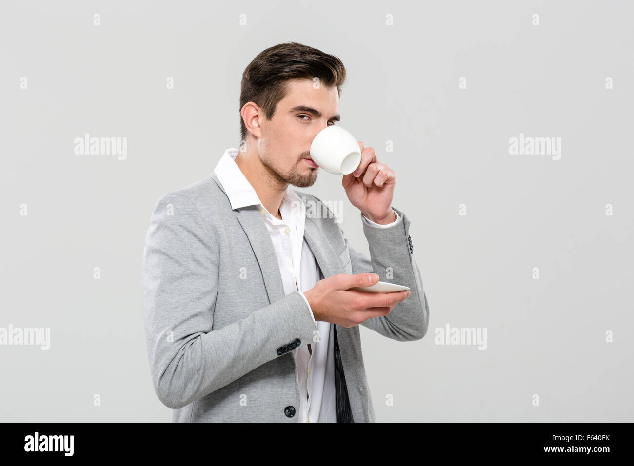 Attraente bello businessman in giacca grigia e camicia bianca corree potabile Foto Stock