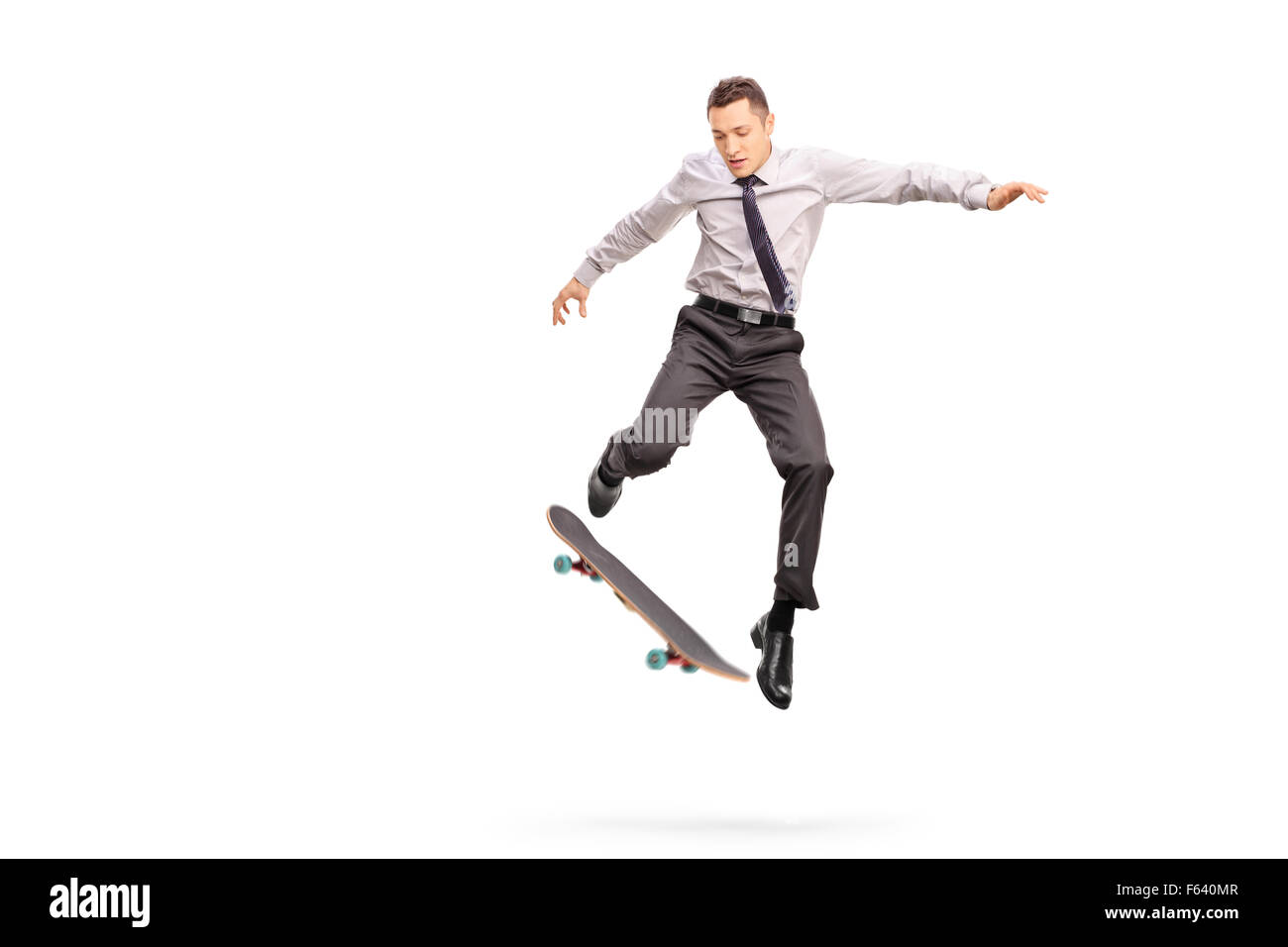 Studio shot di un giovane imprenditore di eseguire un trick con un colpo di skateboard a mezz aria isolata su sfondo bianco Foto Stock