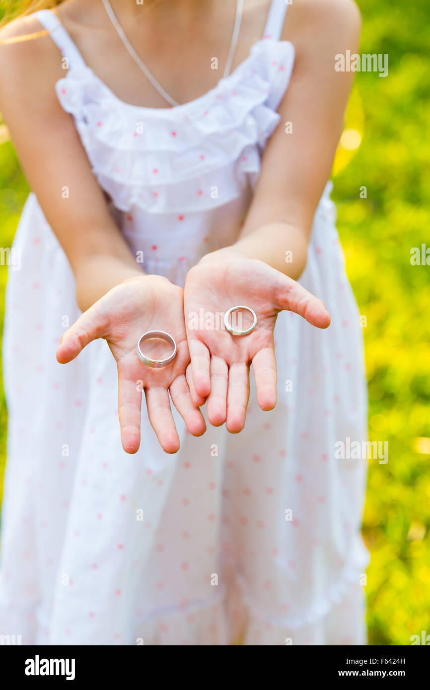 Ragazza giovane azienda la sposa e lo sposo gli anelli di nozze nella sua mano appena prima della cerimonia. Foto Stock