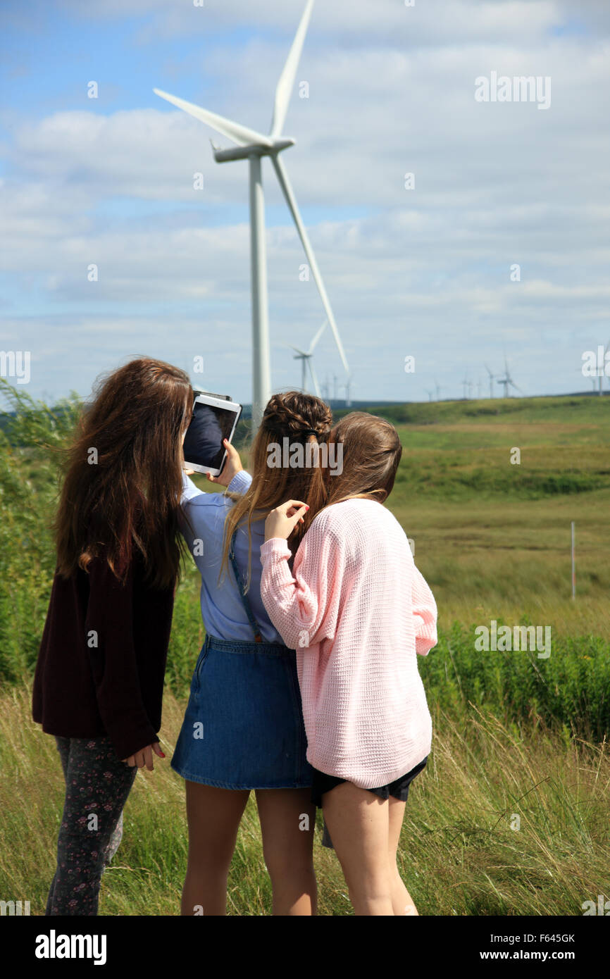 Le ragazze adolescenti prendendo un selfie ad una fattoria eolica Foto Stock