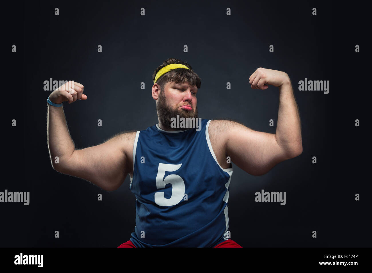 Fat Man mostra il suo muscolo su sfondo grigio Foto Stock