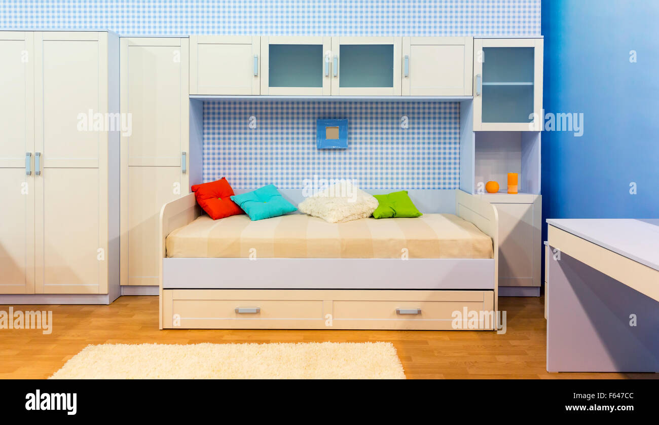 Luminosa camera da letto con un letto con cuscini e armadietto Foto Stock