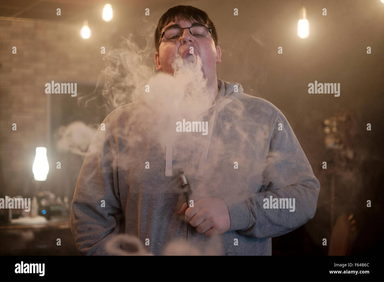 L uomo si brucia una fuga di nuvole di vapore mentre vaping utilizzando un dispositivo elettronico England Regno Unito Foto Stock