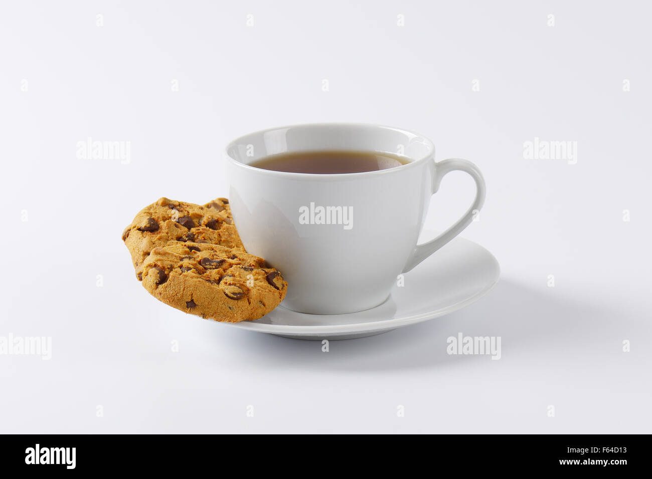 Tazza di tè e biscotti con scaglie di cioccolato su sfondo bianco Foto Stock