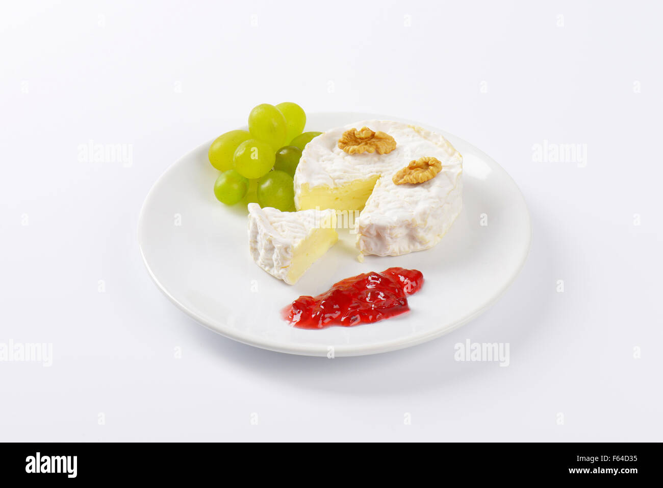 Formaggio Brie con noci, uva e marmellata sulla piastra bianca Foto Stock