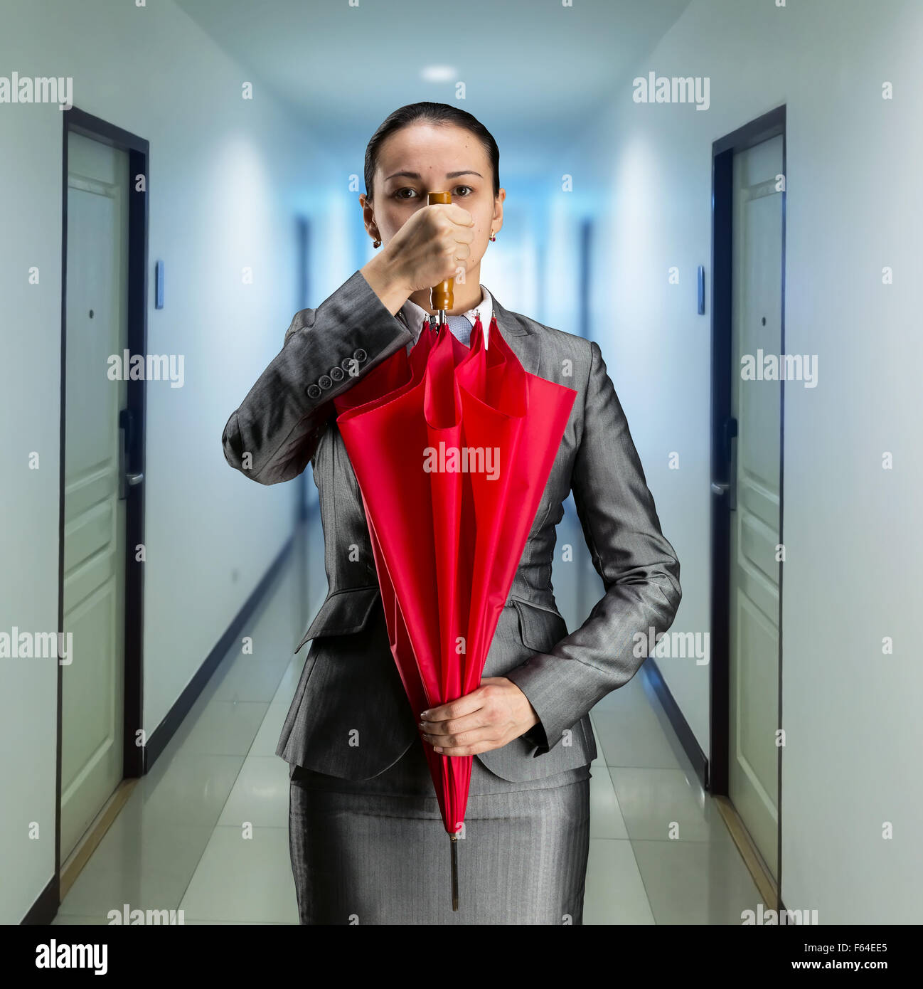 Imprenditrice con ombrello chiuso in ufficio Foto Stock