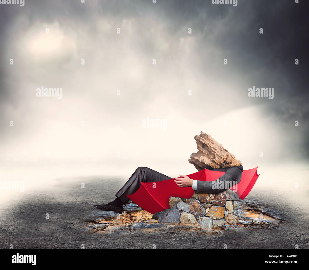 Imprenditore Deppressed siede nell'ombrello tra le rocce Foto Stock