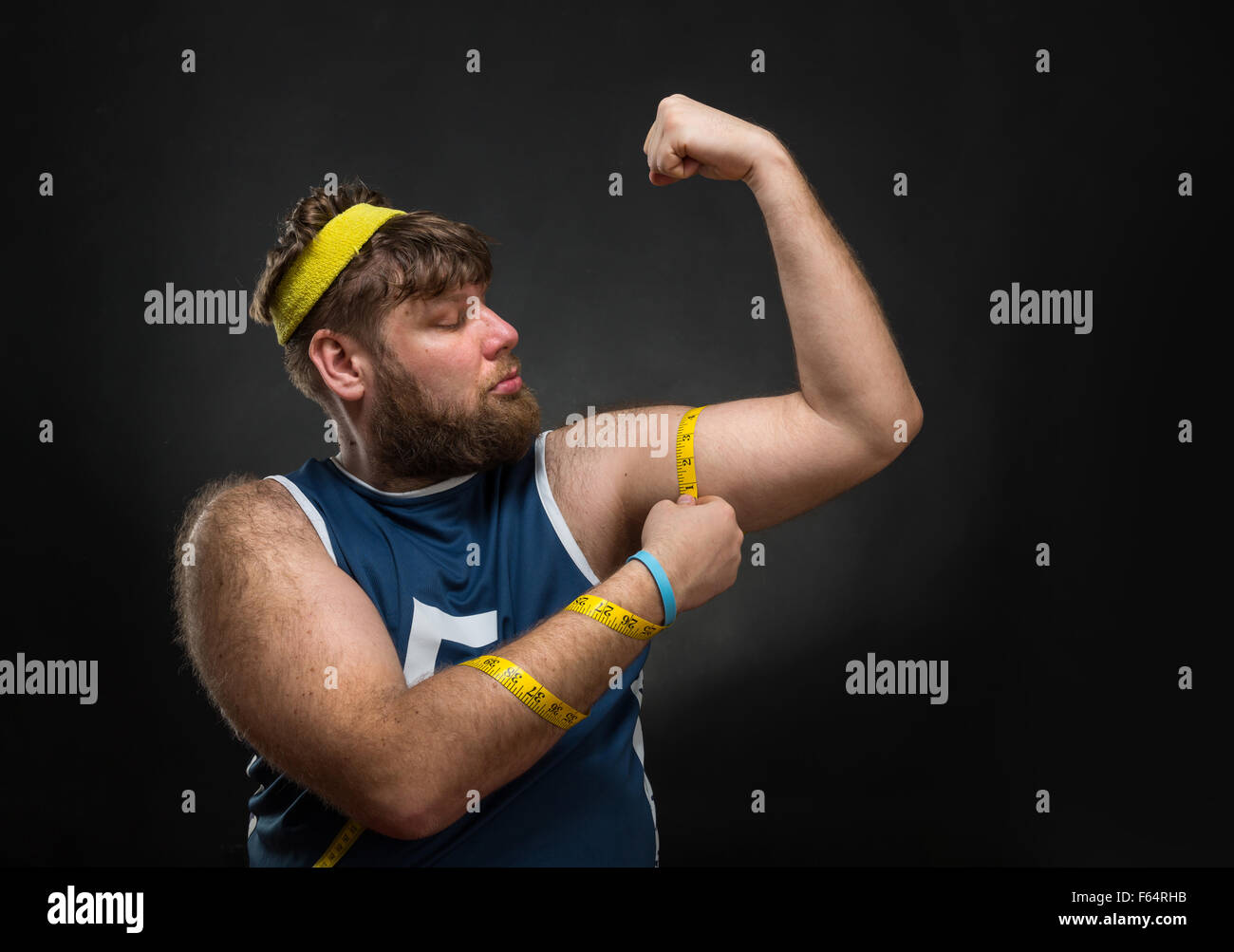 Fat Man misurando il suo muscolo a mano Foto Stock