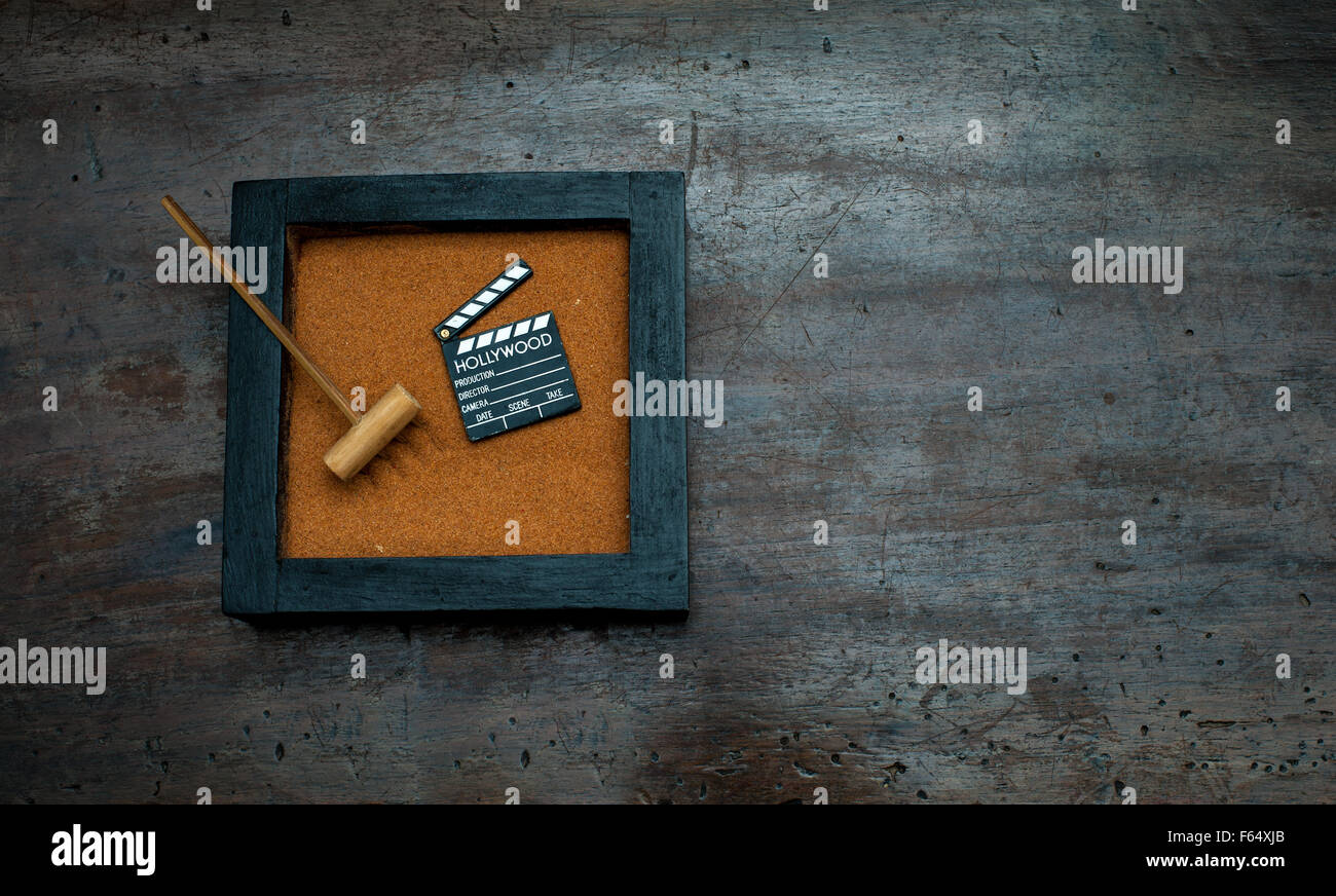 Giardino Zen con rastrello e movie clapper bordo, sabbia arancione su invecchiato in legno raschiato Foto Stock