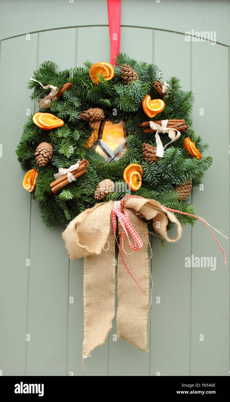 Una ghirlanda di Natale,o corona, dotate di stecche di cannella ed essiccato fettine di arancia si blocca su un cottage porta in Inghilterra, Regno Unito Foto Stock