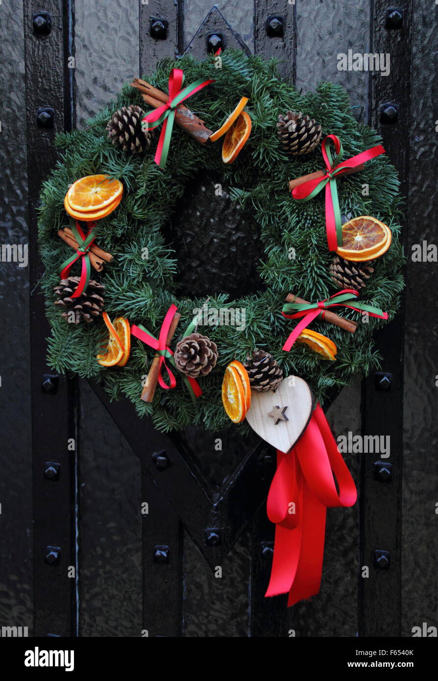 Una ghirlanda di Natale, o corona appeso al legno porta anteriore di un cottage in un villaggio inglese Foto Stock