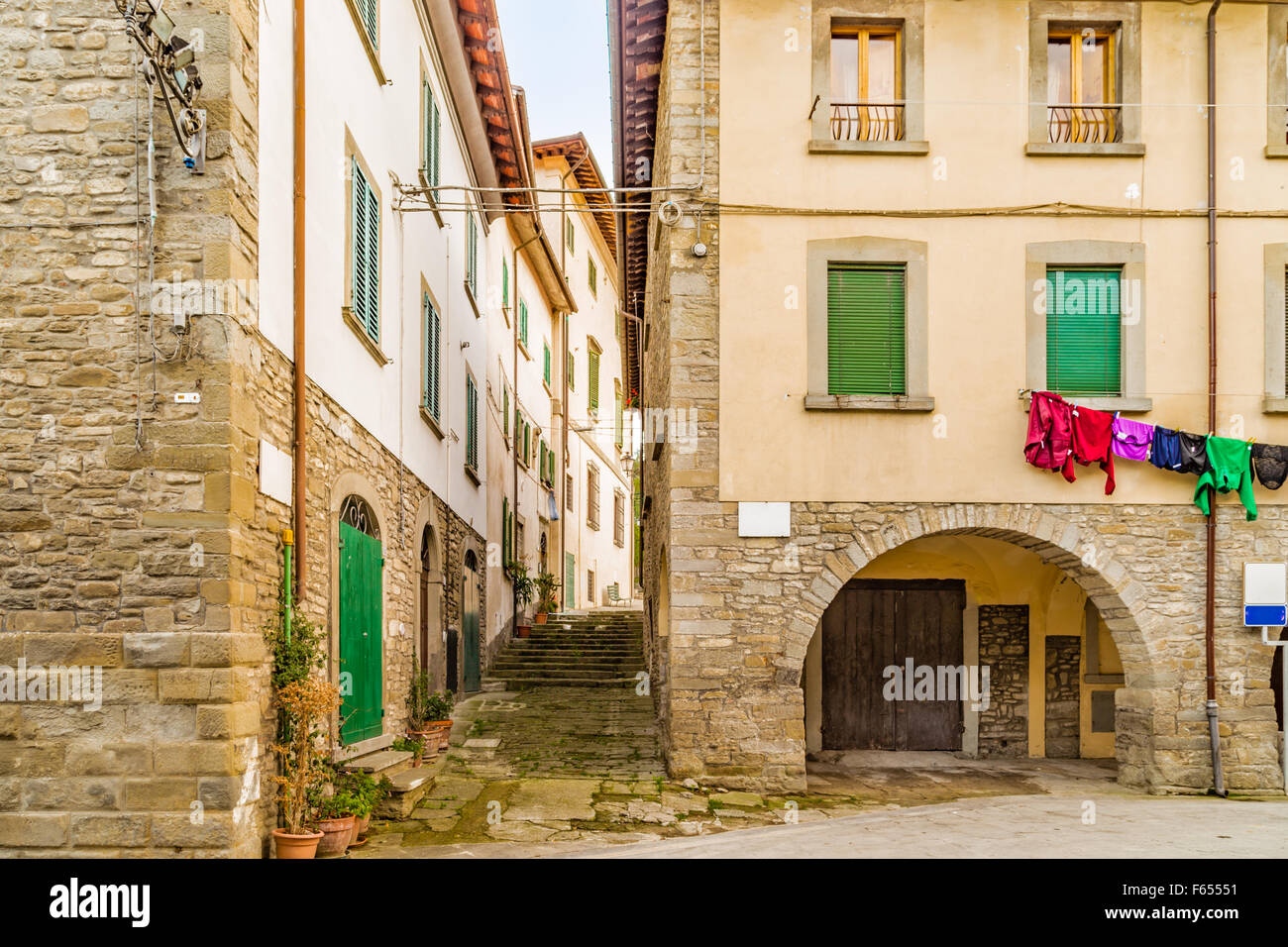 Vicoli nel borgo medievale di borgo di montagna in Toscana caratterizzato da case con pareti di pietre derivata dal Rinascimento: tipiche italiane dettagli come vasi di fiori e cavo di essiccazione con i vestiti appesi ad asciugare Foto Stock