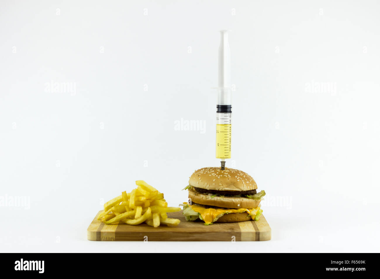 Siringa puming liquido giallo in un hamburger, su sfondo bianco Foto Stock