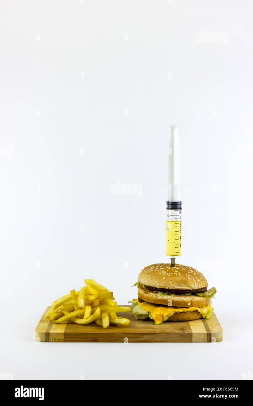 Siringa puming liquido giallo in un hamburger, su sfondo bianco Foto Stock
