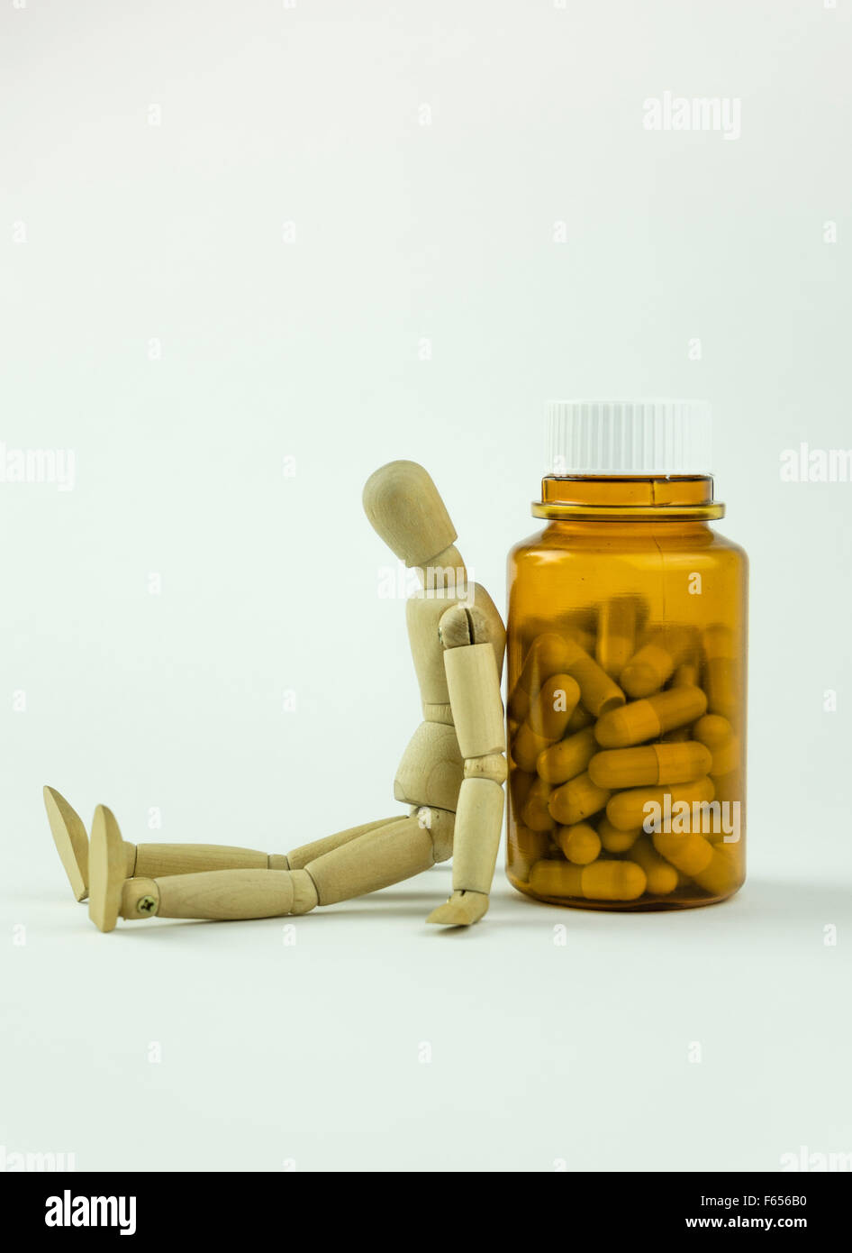 Il burattino di legno seduto accanto a una bottiglia di pillole Foto Stock