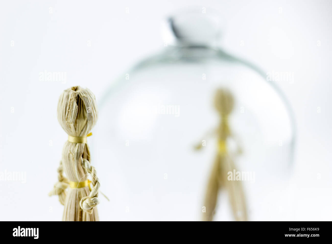Uomo e donna bambole di paglia, diviso da una campana di vetro, su sfondo bianco Foto Stock