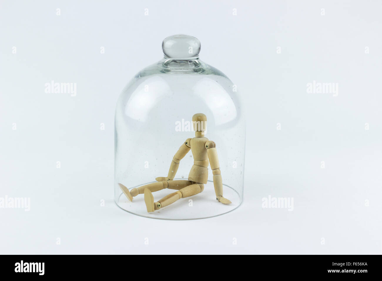 Legno Puppet intrappolato in una campana di vetro gabbia, su sfondo bianco Foto Stock