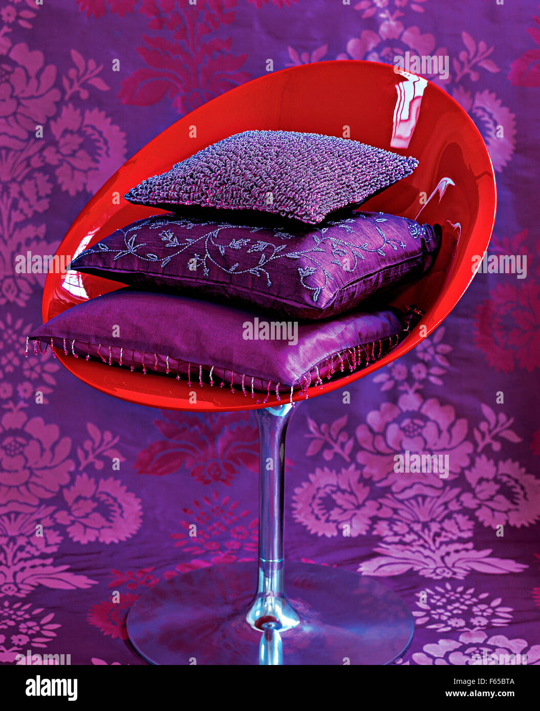 Pila di raso color porpora e cuscini di seta rosso sulla sedia della shell Foto Stock
