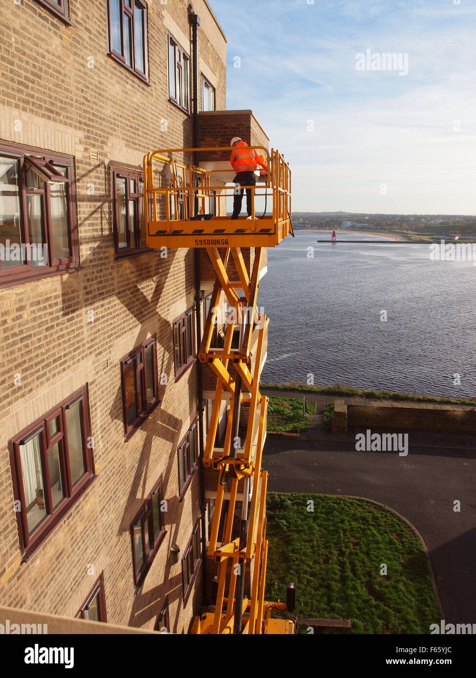 Newcastle Upon Tyne, 12 novembre 2015, UK Meteo.soleggiate di Tynemouth lavoratori come utilizzare una piattaforma per pulire le finestre dopo i lavori di ristrutturazione è stato completato su un complesso di appartamenti. Credito: James Walsh Alamy/Live News Foto Stock