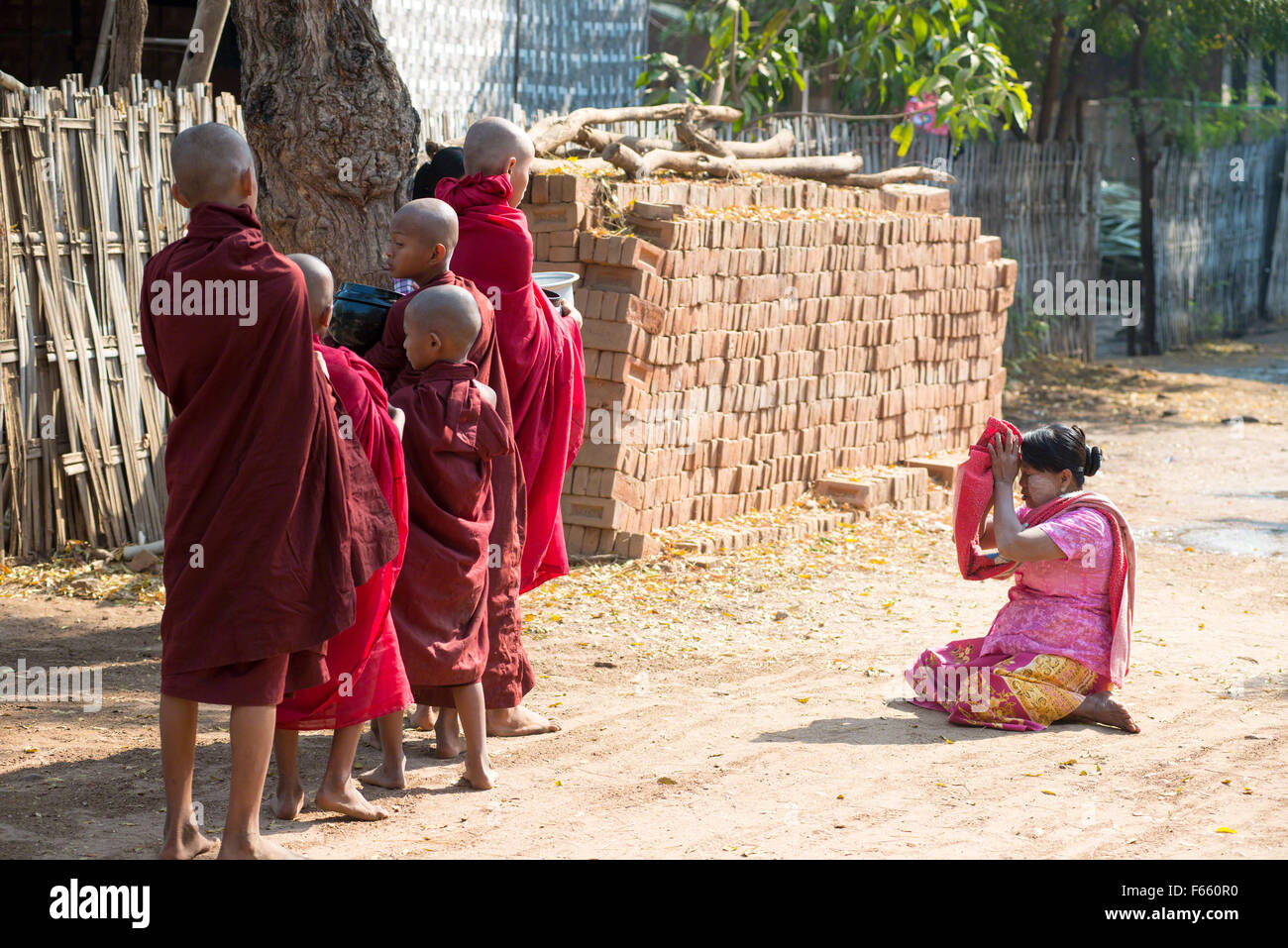 Una donna dà elemosina ai monaci novizio il Mar 2, 2015 in Bagan, Myanmar. Questo comportamento può essere visto tutti i giorni in ogni villaggio. Foto Stock