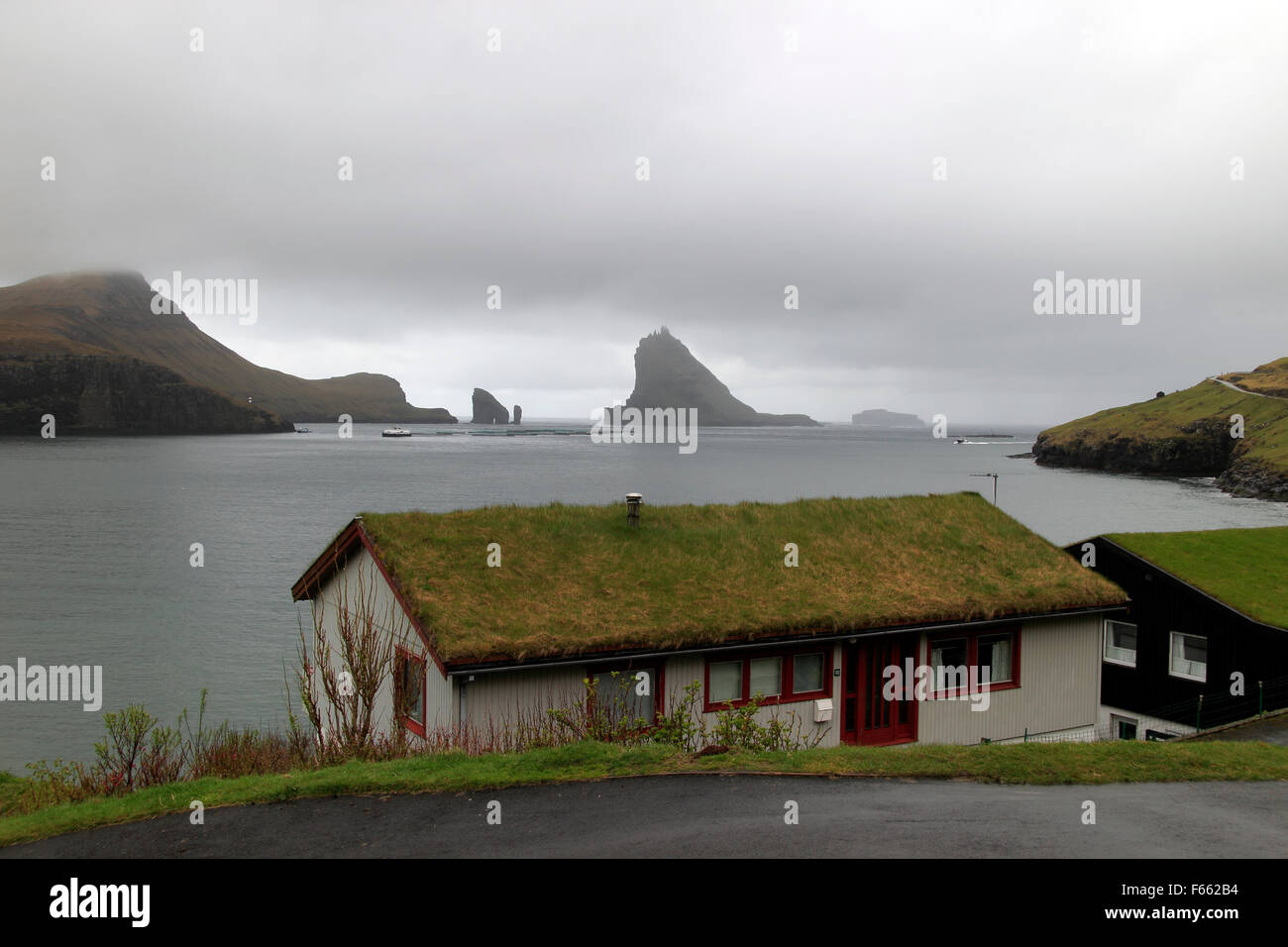 Tappeto erboso tradizionale tetto case del borgo di Bøur, con Tindhólmur in background nei pressi di Sørvágur Vágar Island Isole Faerøer Foto Stock