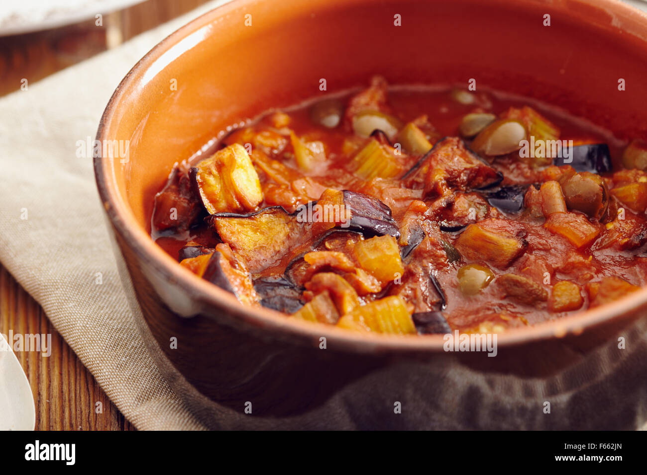 Caponata di melanzane, tradizionale piatto siciliano. Servita in un classico della coppa in ceramica su un tovagliolo su un vecchio tavolo di legno. Circondato Foto Stock Caponata di melanzane, tradizionale piatto siciliano. Servita in un classico della coppa in ceramica su un tovagliolo su un vecchio tavolo di legno. Circondato Foto Stock