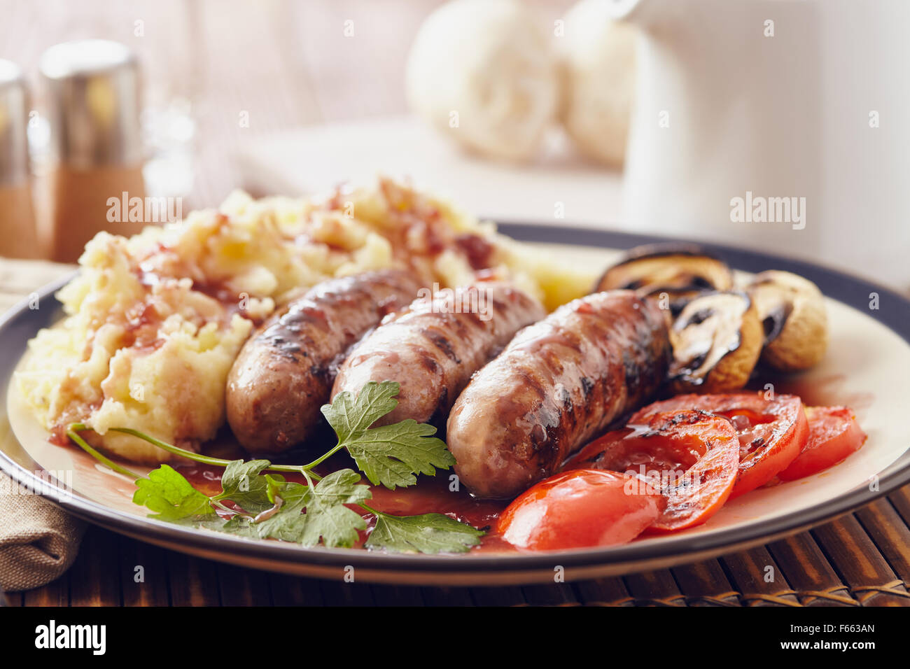 Salsicce e mash piatto con funghi alla griglia e pomodori Foto Stock