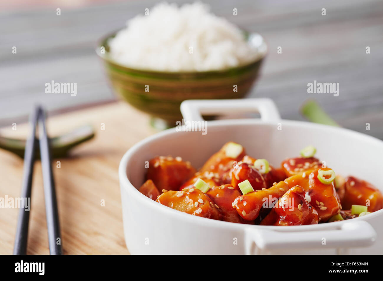 Il pollo al forno di sesamo su un bambù tagliere con riso basmati Foto Stock