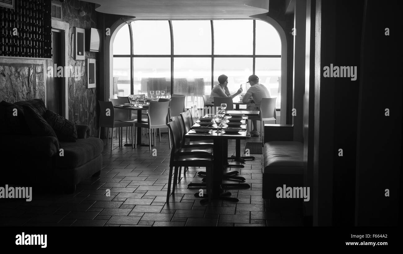 Un uomo e una donna seduti a un tavolo in un ristorante con una finestra dietro di loro. Foto Stock