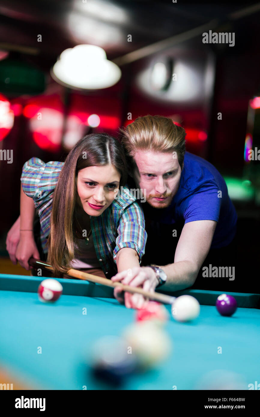 Giovane uomo bello e donna flirtare mentre giocando a biliardo Foto Stock