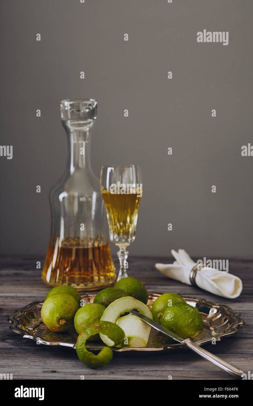 Il limoncello in un classico ed elegante e bottiglia di vetro con limone verde su un argento piatto con un coltello Foto Stock