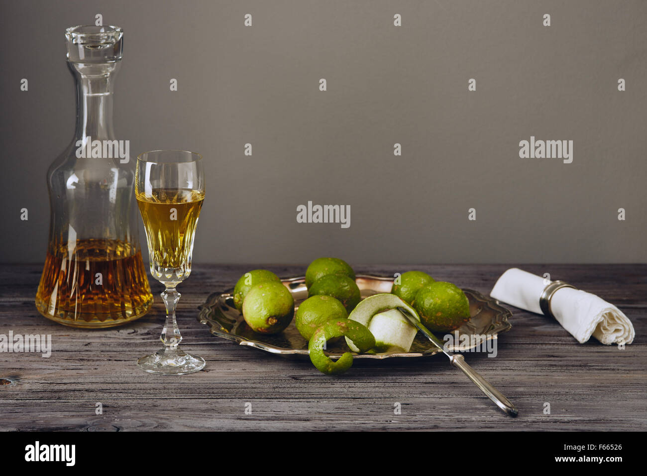 Il limoncello in un classico ed elegante e bottiglia di vetro con limone verde su un argento piatto con un coltello Foto Stock