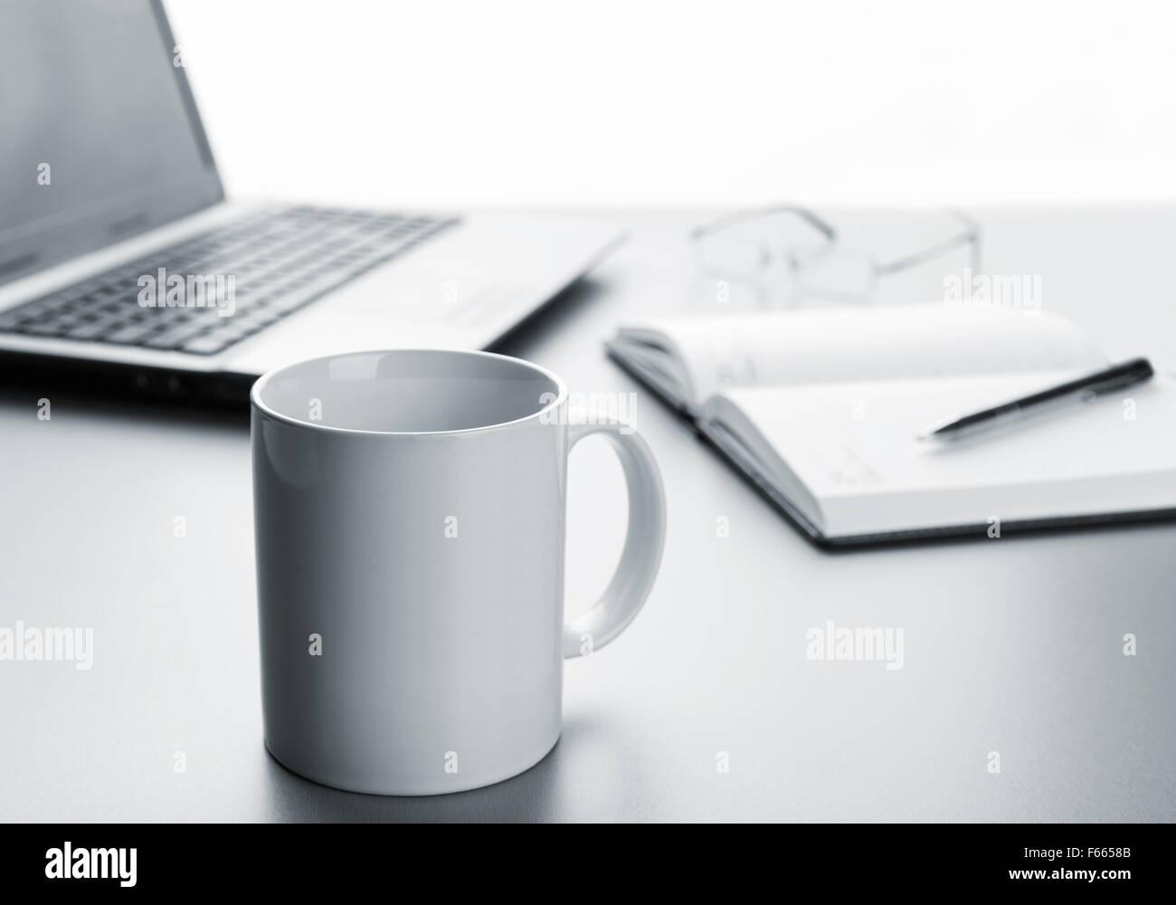 Tazza bianca, laptop, notebook e penna sul tavolo Foto Stock