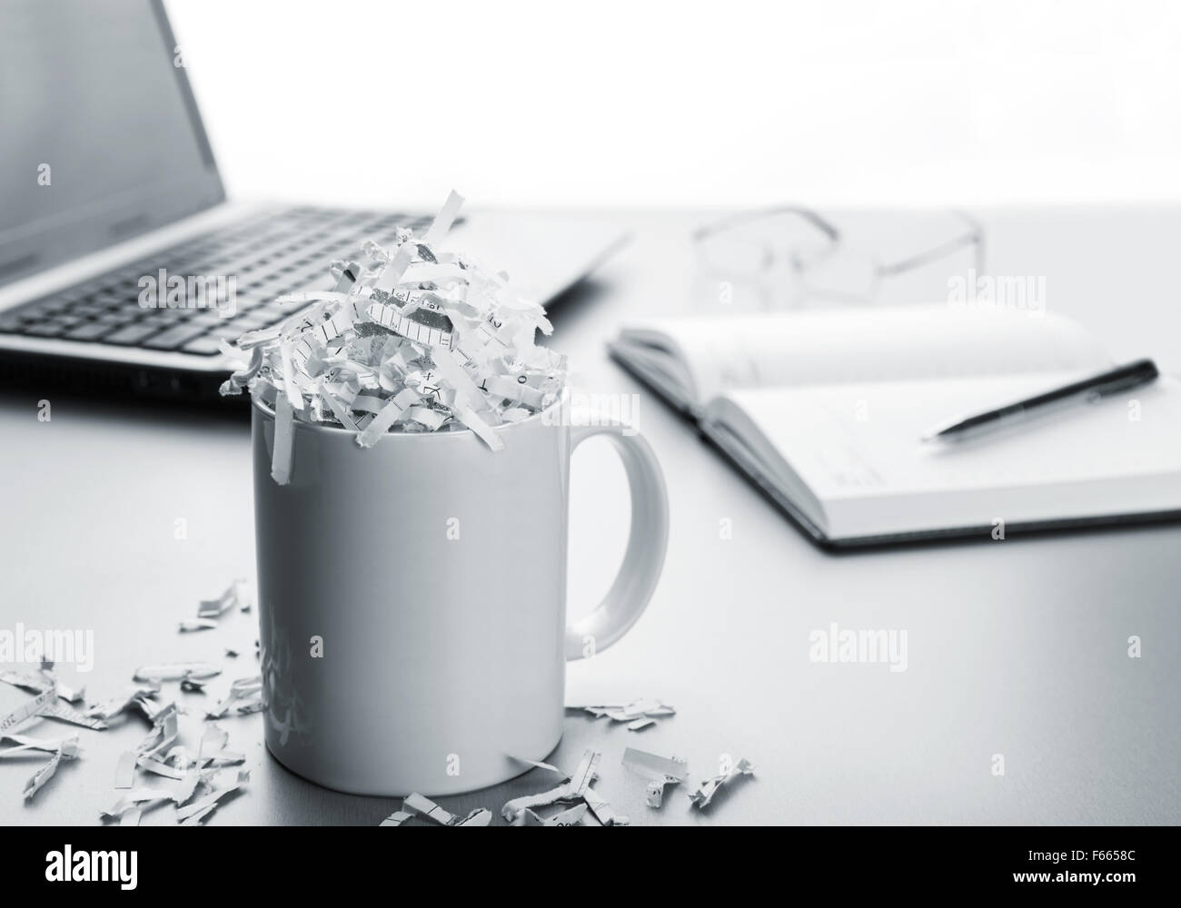 Coppa piena di carta tagliuzzata e laptop, notebook, penna Foto Stock
