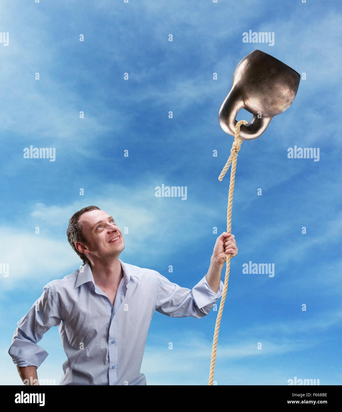 Strano uomo detiene un kettlebell come un ballon contro sky Foto Stock