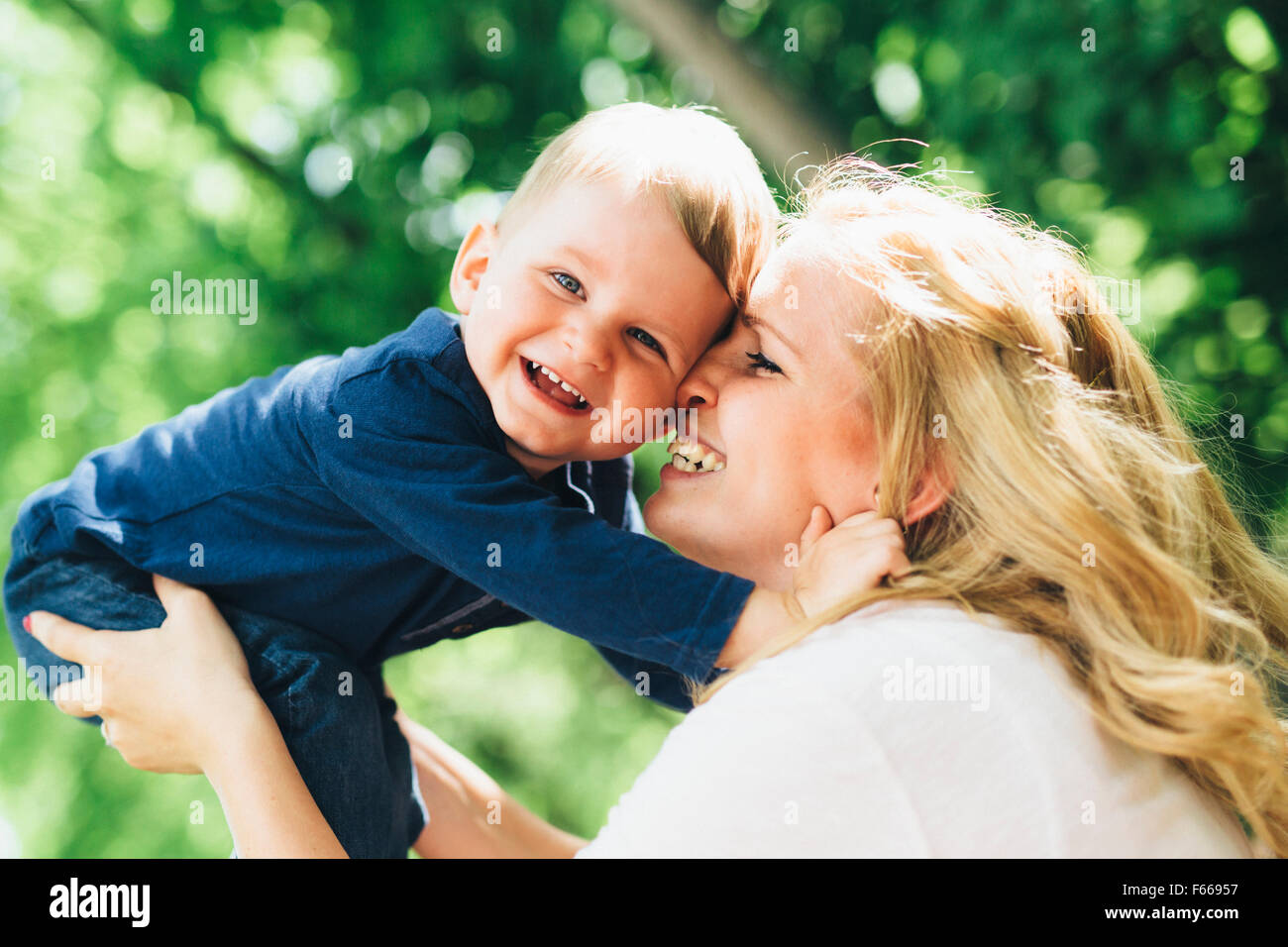 Madre sorridente ridendo e giocando con il suo bambino all'aperto su un bel giorno di estate Foto Stock
