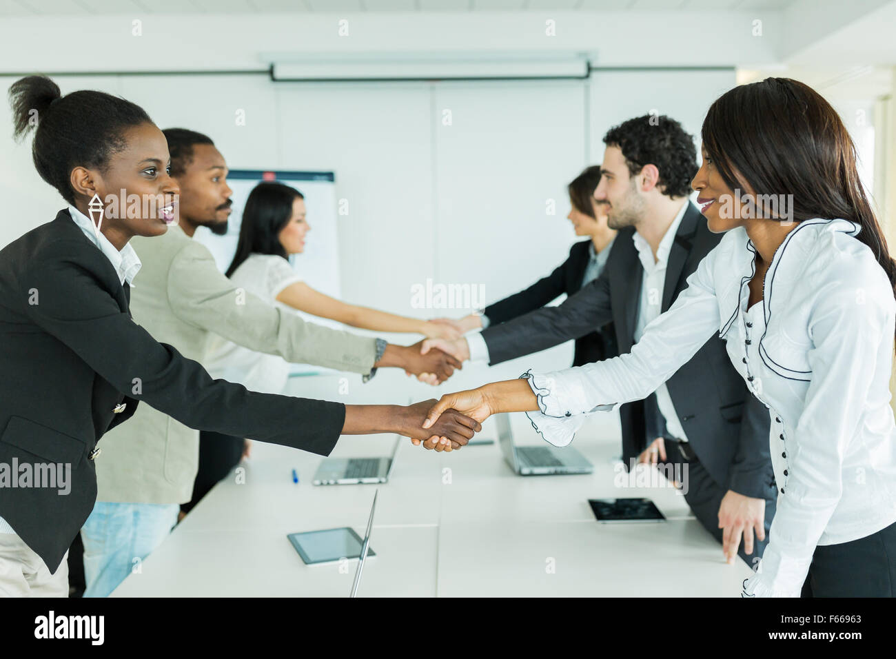 La gente di affari stringono le mani prima di sedersi a un tavolo da conferenza Foto Stock