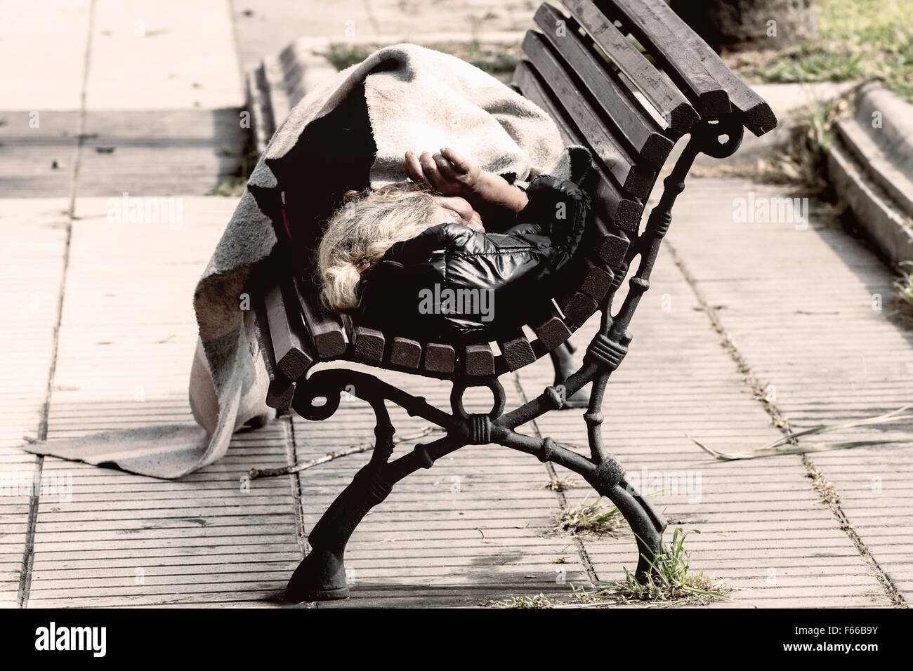 Anziani senzatetto donna che dorme su una panchina nel parco. Foto Stock