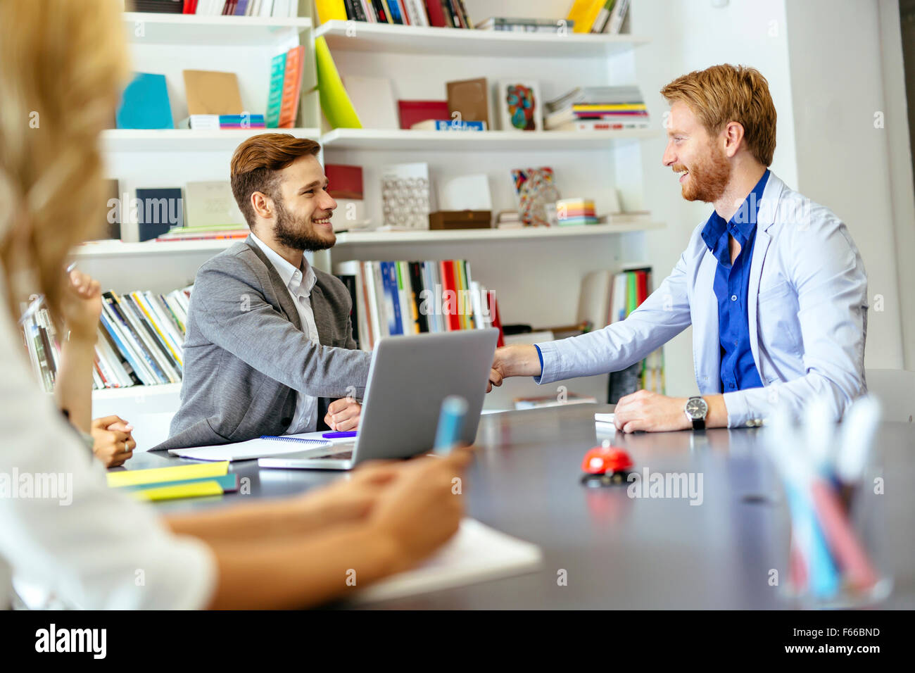 Gli imprenditori si stringono la mano in ufficio con i colleghi e lo staff di sedere a tavola con loro Foto Stock