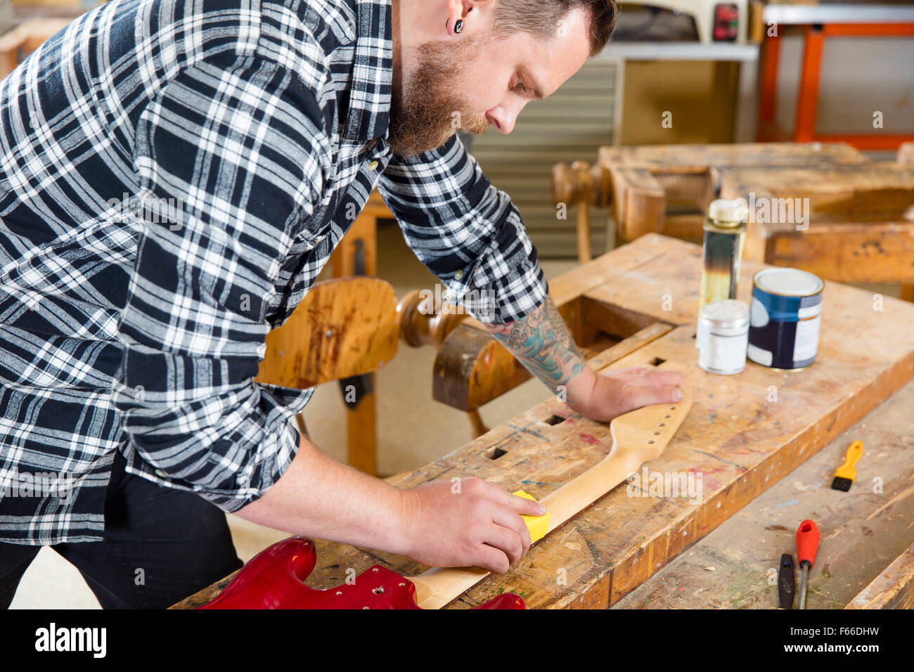 Artigiano levigazione di un collo per chitarra in legno in officina Foto Stock
