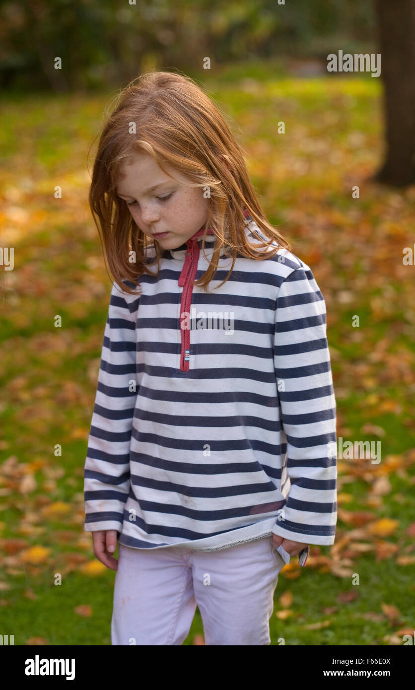 Un dolce bambina con autunnale di capelli colorati è camminare un sfondo autunnale. Foto Stock