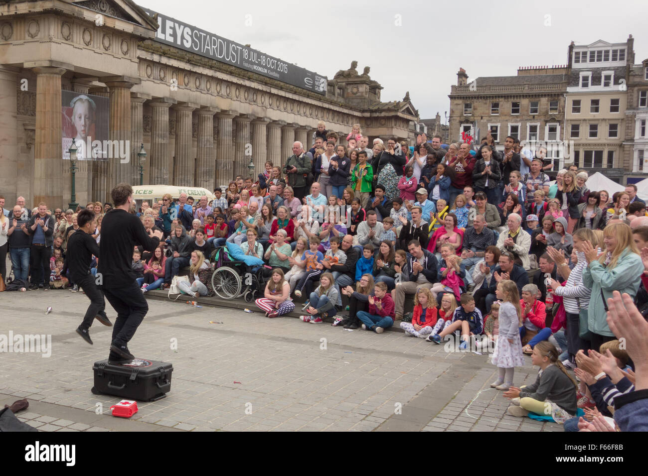 La folla godendo di Edinburgh Fringe Festival 2015 agire "Funny ossa Cestino' al di fuori della Scottish National Gallery Foto Stock