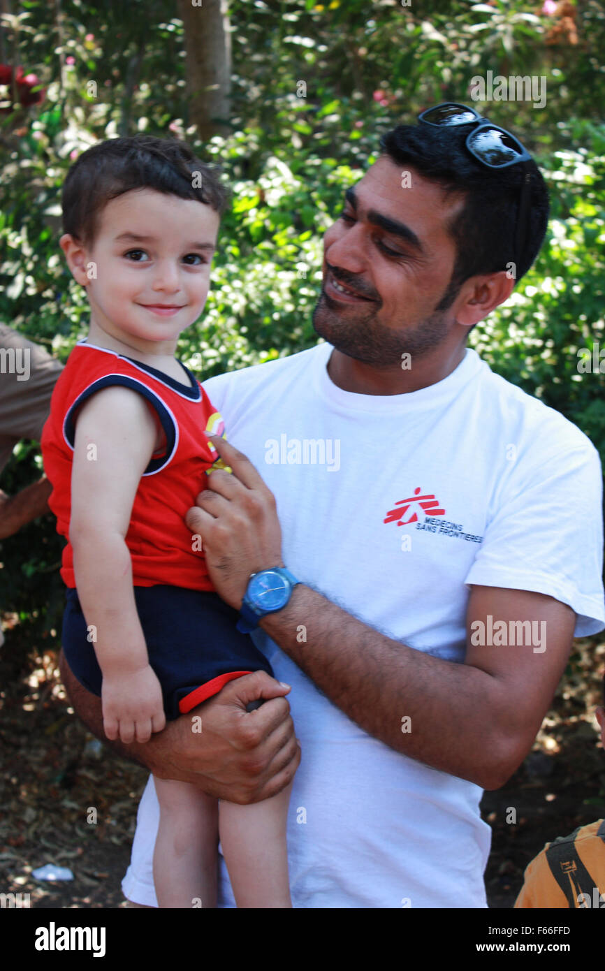 Atene. Xvii Sep, 2015. La foto scattata il 7 settembre 17, 2015 mostra Farhad Agajan tenendo un rifugiato boy sull'isola greca di Kos. Come traduttore per Medici Senza Frontiere (Medecins sans Frontieres, MSF) sull'isola di Kos, Farhad ha per sei mesi prestato la sua voce per i nuovi arrivati e facilita in ogni modo possibile il loro soggiorno breve in debito-laden Grecia prima di continuare su per più prospere del centro e nord Europa paesi. La fotografia va con la storia "Intervista: aprire passaggi sicuri per i rifugiati, aiuto fine guerre: traduttore afghani". © Dimitris Roubis/Xinhua/Alamy Live News Foto Stock