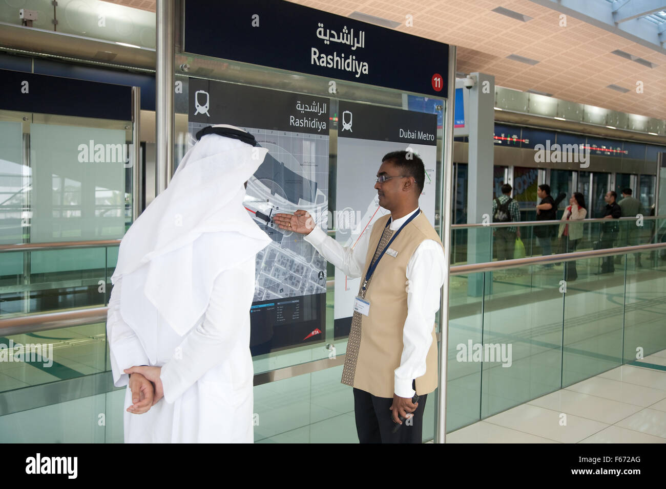 Uomo arabo essendo dato informazioni dal membro del personale della metropolitana di Dubai Foto Stock