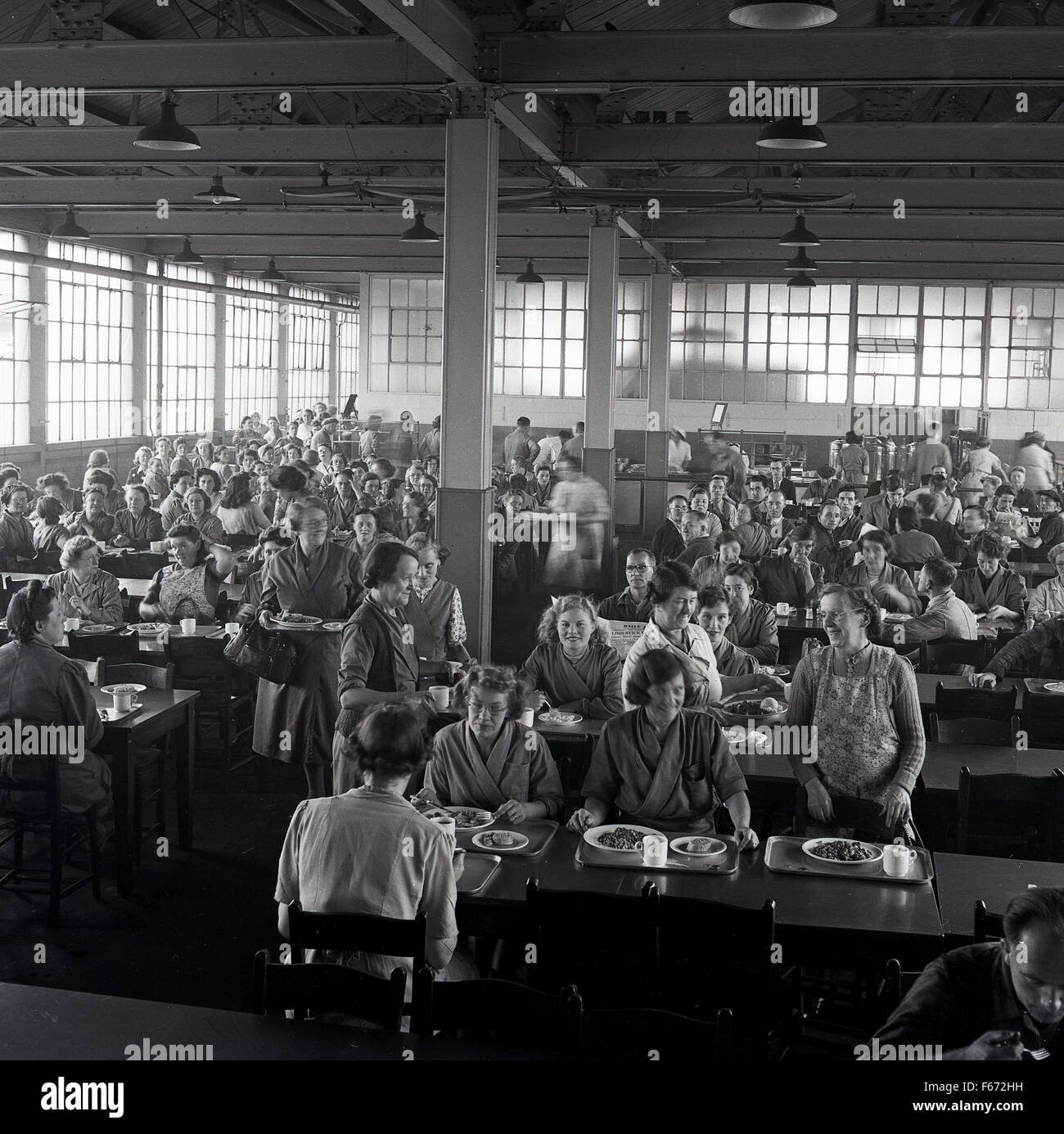 Anni Cinquanta foto storiche che mostra un folto gruppo di lavoratori in fabbrica a pranzo nella mensa per il personale. Foto Stock