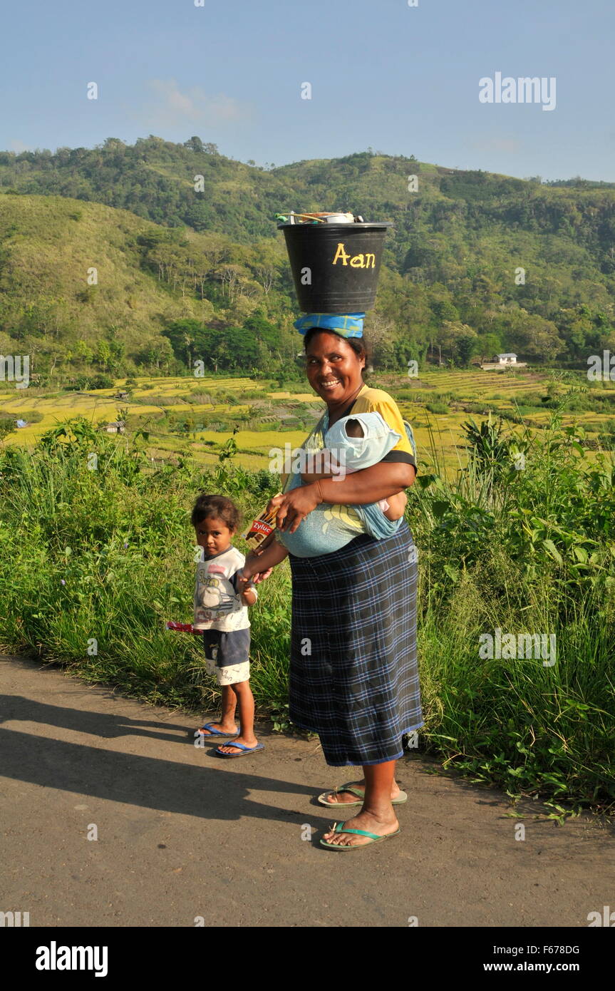 La donna a piedi lungo la strada con il bambino, Indonesia Foto Stock