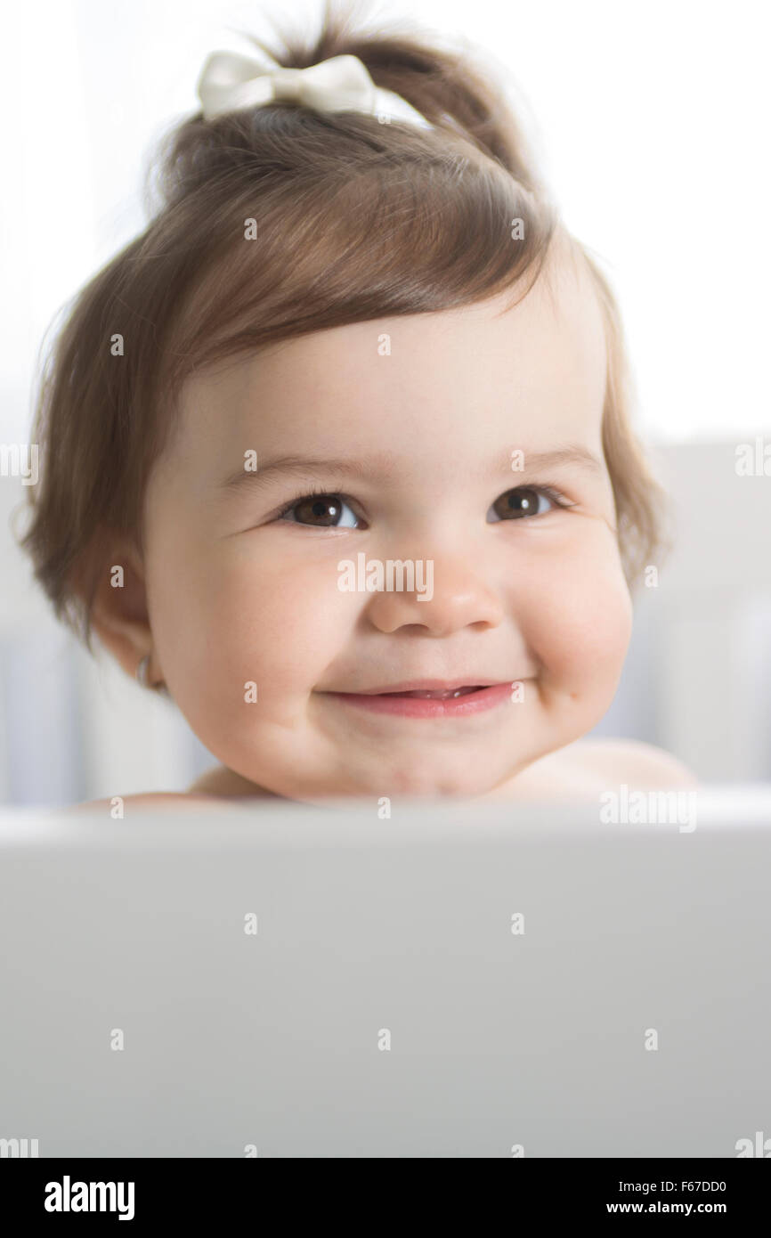 Infant baby in appoggio e giocare nel suo piccolo letto per bambino Foto Stock