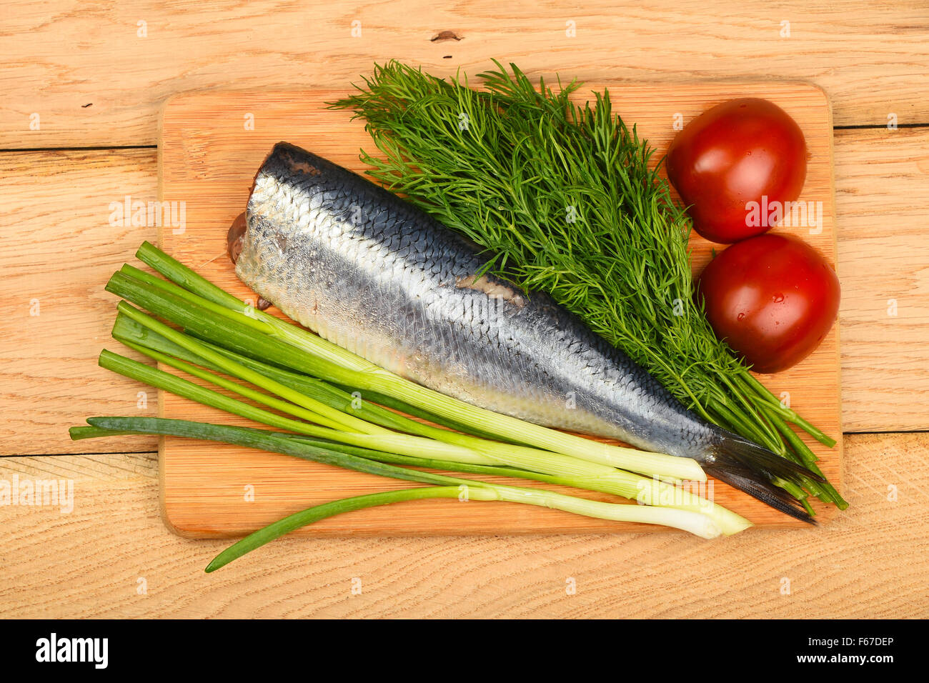 Aringa a doppio filetto con la cipolla, l'aneto e pomodori sul bordo di bambù in legno vintage la superficie del tavolo Foto Stock